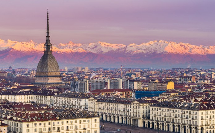 Torino (Turin, Italy): cityscape at sunrise with details of the Mole Antonelliana towering over the city. Scenic colorful light on the snowcapped Alps in the background.
