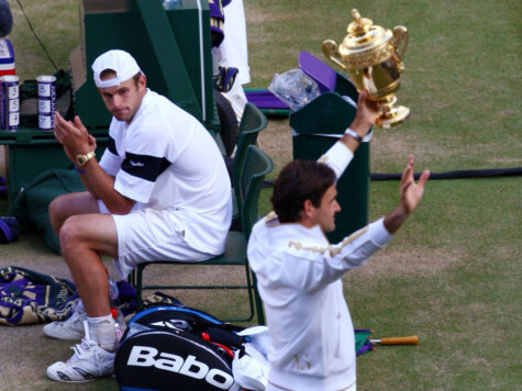 WIMBLEDON, ENGLAND - JULY 05: Andy Roddick of USA looks despondent as Roger Federer of Switzerland celebrates with the trophy during the men's singles final match on Day Thirteen of the Wimbledon Lawn Tennis Championships at the All England Lawn Tennis and Croquet Club on July 5, 2009 in London, England. Federer won 5-7, 7-6, 7-6, 3-6, 16-14. (Photo by Julian Finney/Getty Images) ORG XMIT: 87978030 GTY ID: 78030MT394_The_Champions